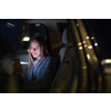Young woman with her cell phone sitting in the backseat of a car, getting ready to travel (color toned image; shallow DOF)