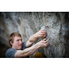 A rock climber climbing on a boulder rock outdoors. Group of friends involved in sports outside.