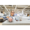 Pretty, young woman choosing the right furniture for her apartment in a modern home furnishings store (color toned image; shallow DOF)