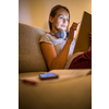 Pretty, young woman working at home in the evening - using her tablet computer as well as bluetooth headphones, writing down some ideas for tomorrow