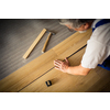 DIY, repair, building and home concept - close up of male hands lying parquet floor board/laminate flooring (shallow DOF; color toned image)