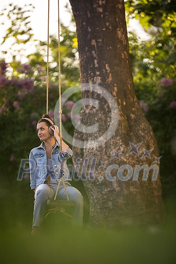 Pretty, young woman with headphones outdoors, in a lovely park, enjoyig the hi-fi quality sound, listening to her favorite songs (color toned image)