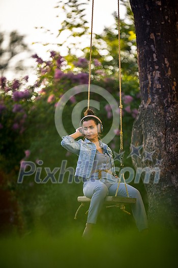 Pretty, young woman with headphones outdoors, in a lovely park, enjoyig the hi-fi quality sound, listening to her favorite songs (color toned image) Pretty, young woman with headphones outdoors, in a lovely park, enjoyig the hi-fi quality sound, listening to her favorite songs (color toned image)