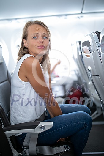 Young happy woman aboard an airplane during flight - not feeling quite well Young happy woman aboard an airplane during flight - not feeling quite well