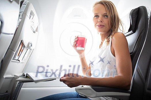 Young happy woman taking selfie photo with passport document sitting on the aircraft seat near a window during the flight in the airplane Young happy woman taking selfie photo with passport document sitting on the aircraft seat near a window during the flight in the airplane