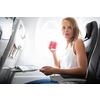 Young happy woman taking selfie photo with passport document sitting on the aircraft seat near a window during the flight in the airplane