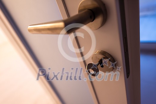 close up of door handle in room interior with Key in the lock close up of door handle in room interior with Key in the lock