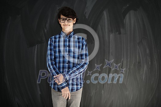 portrait of smart looking arab teenager with glasses wearing a hat in casual school look against black chalkboard background portrait of smart looking arab teenager with glasses wearing a hat in casual school look against black chalkboard background