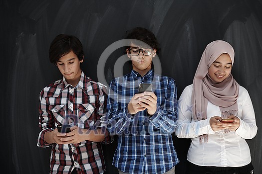 arab teenagers group using smart phones for social media networking against black chalkboard arab teenagers group using smart phones for social media networking against black chalkboard