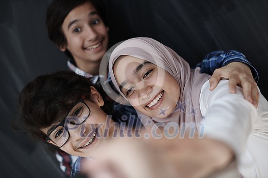 group of arab teens taking selfie photo on smart phone with black chalkboard in background group of arab teens taking selfie photo on smart phone with black chalkboard in background