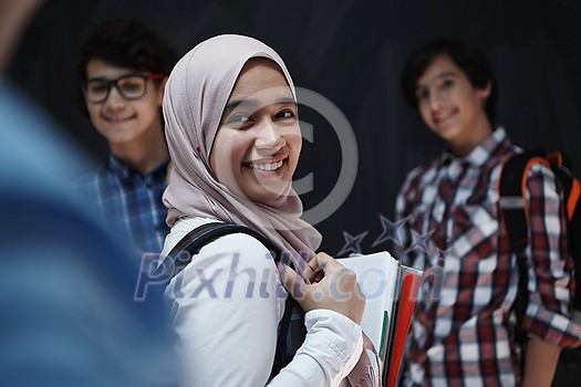 Arabic teenagers, students group portrait against black chalkboard wearing backpack and books in school Arabic teenagers, students group portrait against black chalkboard wearing backpack and books in school