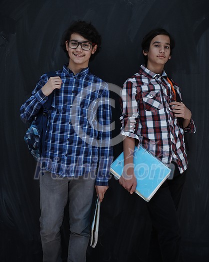 Arabic teenagers group portrait against black chalkboard wearing backpack and books in school classroom Arabic teenagers group portrait against black chalkboard wearing backpack and books in school classroom
