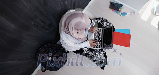arab female student working on laptop from home top view arab female student working on laptop from home top view