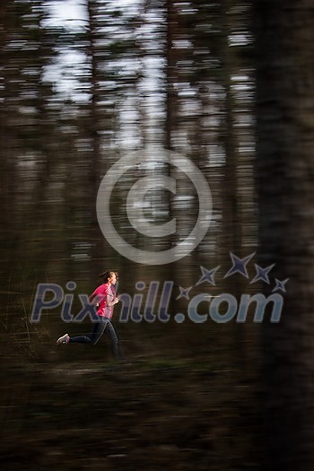 Young woman running outdoors in a forest, going fast (motion blurred image)