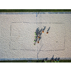 Aerial view of a beach volleyball  pitch with people getting ready for a game in warm morning sun, casting long shadows
