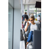 Casual blond young woman using her cell phone while waiting to board a plane at departure gates at international airport.