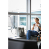 Casual blond young woman using her cell phone while waiting to board a plane at departure gates at international airport.