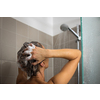 Pretty, young woman taking a long hot shower washing her hair in a modern design bathroom
