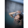 Pretty, young woman taking a long hot shower washing her hair in a modern design bathroom