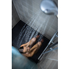 Pretty, young woman taking a long hot shower washing her hair in a modern design bathroom (color toned image)