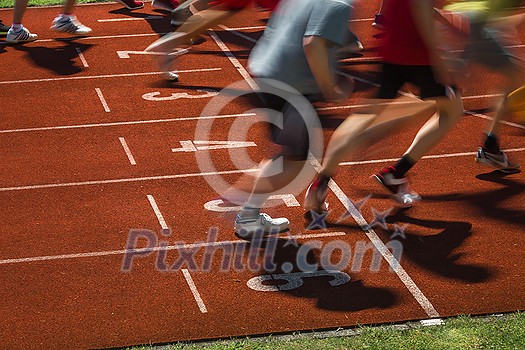 Runners starting a race on a running field (motion blurred image) Runners starting a race on a running field (motion blurred image)