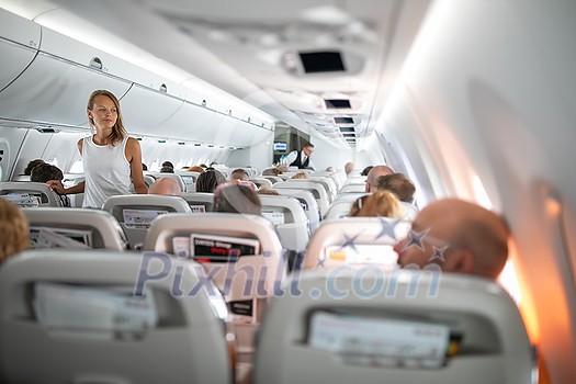 Pretty, young woman aboard an airplane during a lang haul commercial flight - stretching her legs a bit, walking in the aisle Pretty, young woman aboard an airplane during a lang haul commercial flight - stretching her legs a bit, walking in the aisle