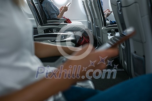 Passengers in abord a commercial flight using their cell phones during flight Passengers in abord a commercial flight using their cell phones during flight