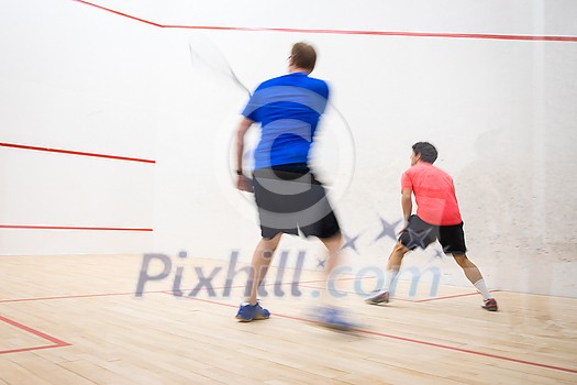 Squash players in action on a squash court (motion blurred image; color toned image) Squash players in action on a squash court (motion blurred image; color toned image)