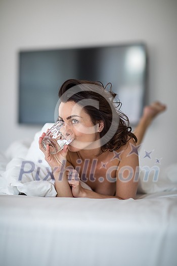 Beautiful young woman using her cell phone in bed on a lovely morning Beautiful young woman using her cell phone in bed on a lovely morning