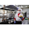 chef cook wearing face protective medical mask for protection from corona virus disease with plate of authentic sandwich at professional restaurant kitchen. Health, safety and pandemic concept in new normal concept