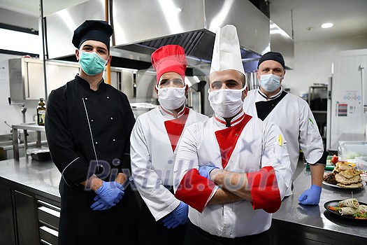 Mixed race team Portrait of group chefs standing together in the kitchen at restaurant wearing protective medical mask and gloves in coronavirus new normal concept Mixed race team Portrait of group chefs standing together in the kitchen at restaurant wearing protective medical mask and gloves in coronavirus new normal concept