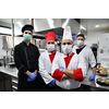 Mixed race team Portrait of group chefs standing together in the kitchen at restaurant wearing protective medical mask and gloves in coronavirus new normal concept