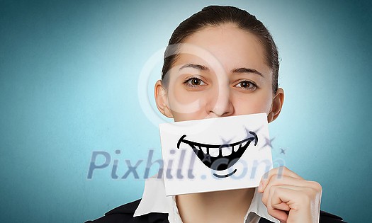 Pretty young girl holding white card with drawn smile with teeth Pretty young girl holding white card with drawn smile with teeth