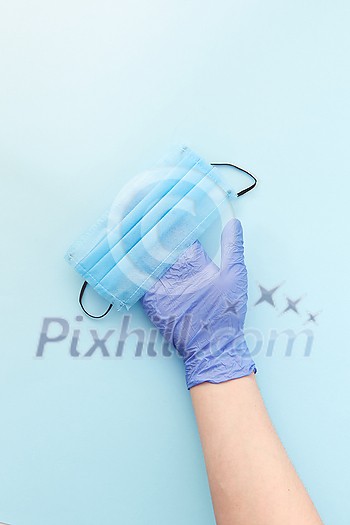 Medical antibacterial protective face mask on a woman's hand in rubber glove on a light blue background from masks. Concept of prevention from respiratory sickness and viruses. Medical antibacterial protective face mask on a woman's hand in rubber glove on a light blue background from masks. Concept of prevention from respiratory sickness and viruses.
