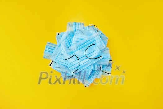 Protective medical antibacterial blue face mask in a small bunch on a yellow background, copy space. Concept of prevention from respiratory sickness and viruses. Protective medical antibacterial blue face mask in a small bunch on a yellow background, copy space. Concept of prevention from respiratory sickness and viruses.
