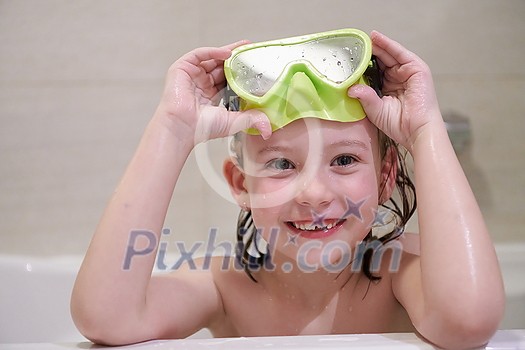little girl with snorkel goggles in the tub while taking a bath in the bathtub, kids hygiene concept and summer vacation in corona virus stay at home little girl with snorkel goggles in the tub while taking a bath in the bathtub, kids hygiene concept and summer vacation in corona virus stay at home
