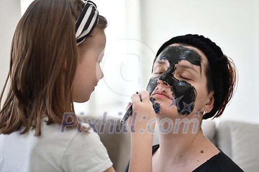 Family at home beauty treatment during coronavirus pandemic stay at home quarantine. Mother and little girl daughter make a facial mask. Family at home beauty treatment during coronavirus pandemic stay at home quarantine. Mother and little girl daughter make a facial mask.