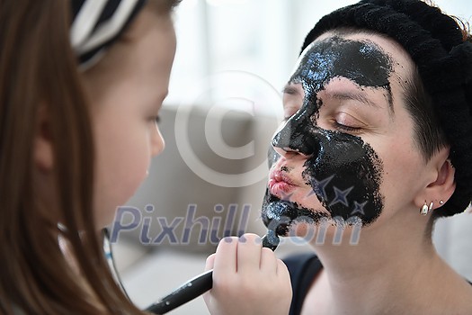Family at home beauty treatment during coronavirus pandemic stay at home quarantine. Mother and little girl daughter make a facial mask. Family at home beauty treatment during coronavirus pandemic stay at home quarantine. Mother and little girl daughter make a facial mask.