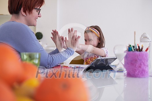 Mother and little daughter playing together drawing creative artwork during coronavirus quarantine measuring time on sandglass and listening music on tablet Mother and little daughter playing together drawing creative artwork during coronavirus quarantine measuring time on sandglass and listening music on tablet