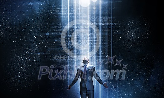 Businessman with hands spread apart standing in light coming from above Businessman with hands spread apart standing in light coming from above