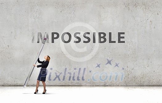 Young businesswoman with huge pencil changing word impossible Young businesswoman with huge pencil changing word impossible