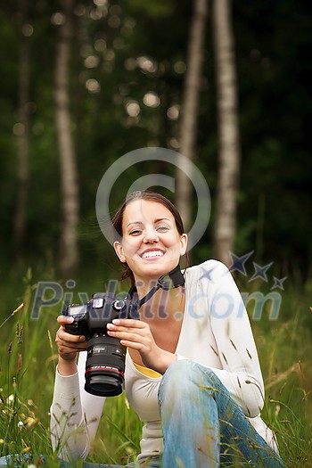 Pretty young woman with a DSLR camera outdoors, taking pictures, having fun learning more about photography
