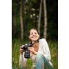 Pretty young woman with a DSLR camera outdoors, taking pictures, having fun learning more about photography