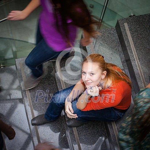 At the university/college - Students rushing up and down a busy stairway - confident pretty young female student looking upwards At the university/college - Students rushing up and down a busy stairway - confident pretty young female student looking upwards