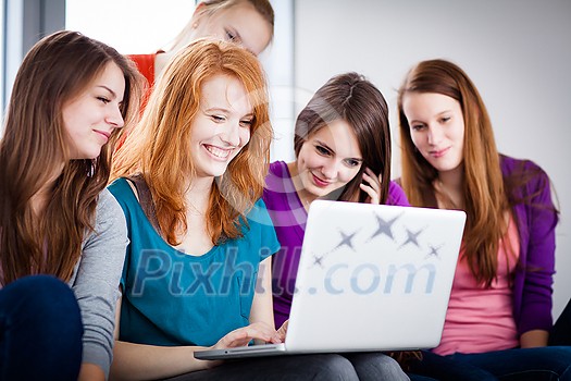 Group of female college students working on their homework/having a chat in between the lectures, using a laptop computer (color toned image) Group of female college students working on their homework/having a chat in between the lectures, using a laptop computer (color toned image)