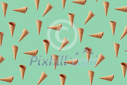 Food pattern from chaotic floating crunchy waffle cones for making fresh sweet ice-cream or desserts against light green background. Food pattern from chaotic floating crunchy waffle cones for making fresh sweet ice-cream or desserts against light green background.