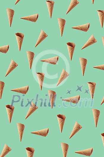 Creative vertical pattern from chaotic flying crunchy waffle cones for making fresh sweet ice-cream or desserts against light green background. Creative vertical pattern from chaotic flying crunchy waffle cones for making fresh sweet ice-cream or desserts against light green background.