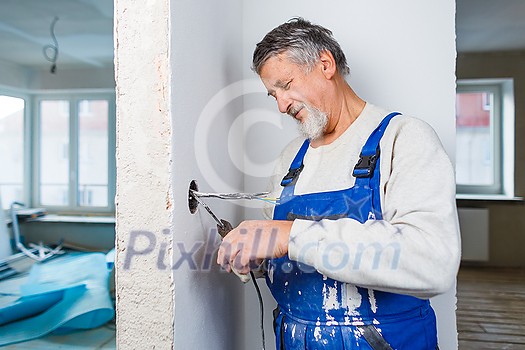 Senior man working on the electrical installations in a freshly renovated appartment Senior man working on the electrical installations in a freshly renovated appartment