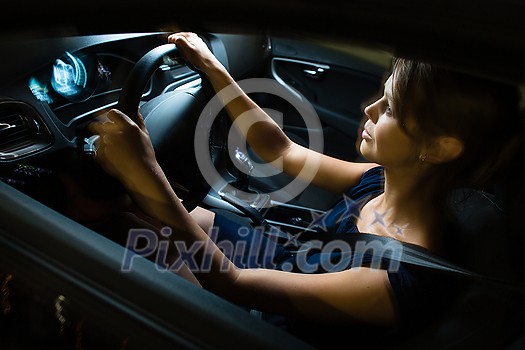 Driving a car at night - pretty, young woman driving her modern car at night, in a city (shallow DOF; color toned image) Driving a car at night - pretty, young woman driving her modern car at night, in a city (shallow DOF; color toned image)