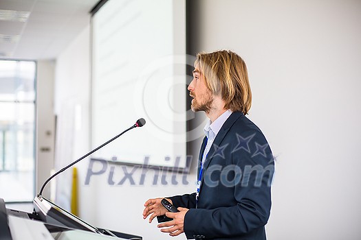Handsome young man giving a speech at a conference Handsome young man giving a speech at a conference
